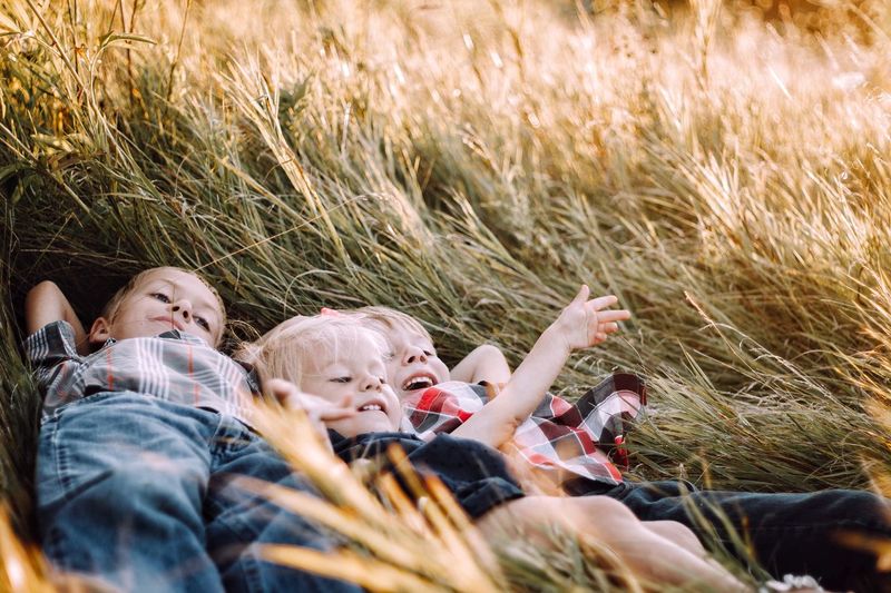 Close-up of siblings lying on grass