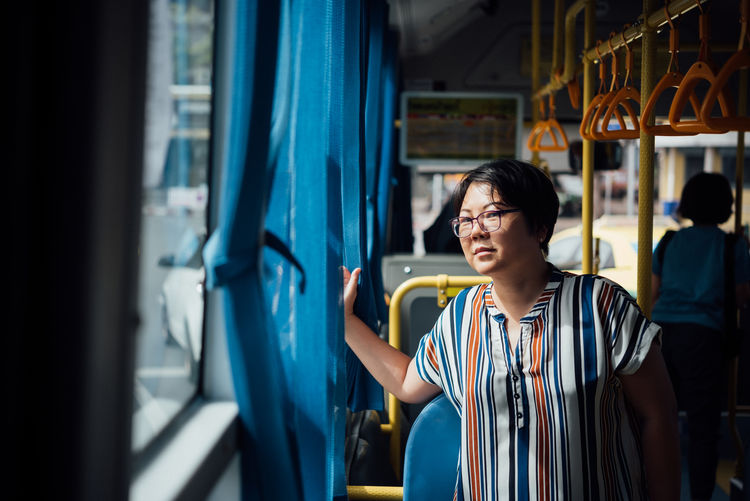 Woman looking through window in bus