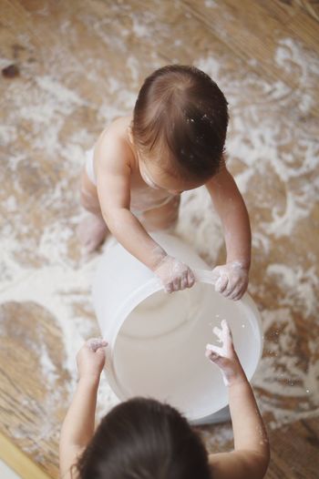 High angle view of toddlers playing with flour at home
