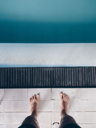 Low section of man standing by swimming pool