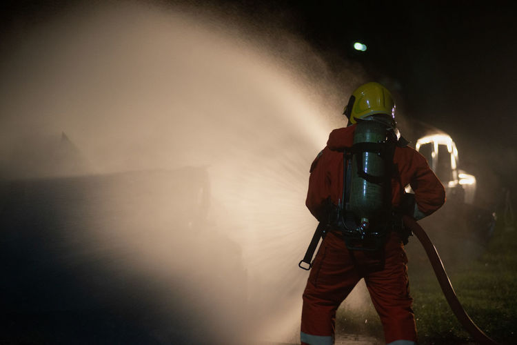 Firefighter holding pipe at night