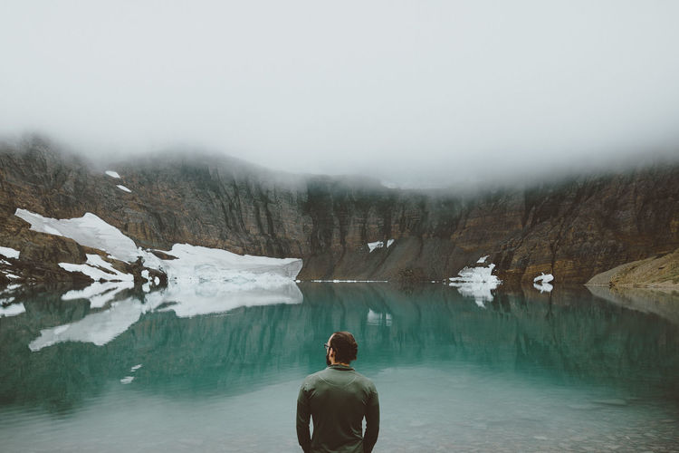 Man standing in front of iceberg lake against clear sky