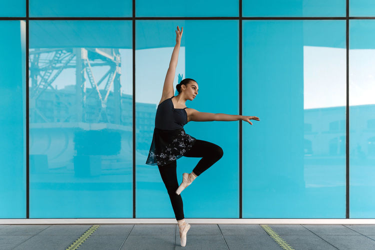 Graceful female dancer practicing against modern building