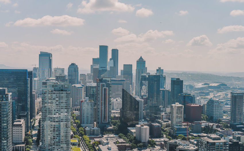 Aerial view of city buildings against cloudy sky