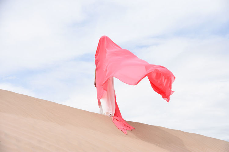 Low angle view of red flag on desert against sky