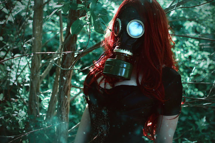 Close-up of woman wearing gas mask standing by trees