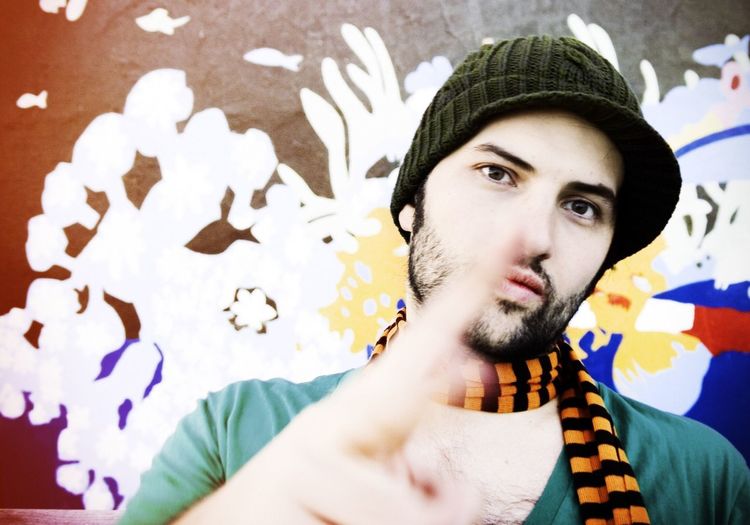 Close-up portrait of young man showing peace sign