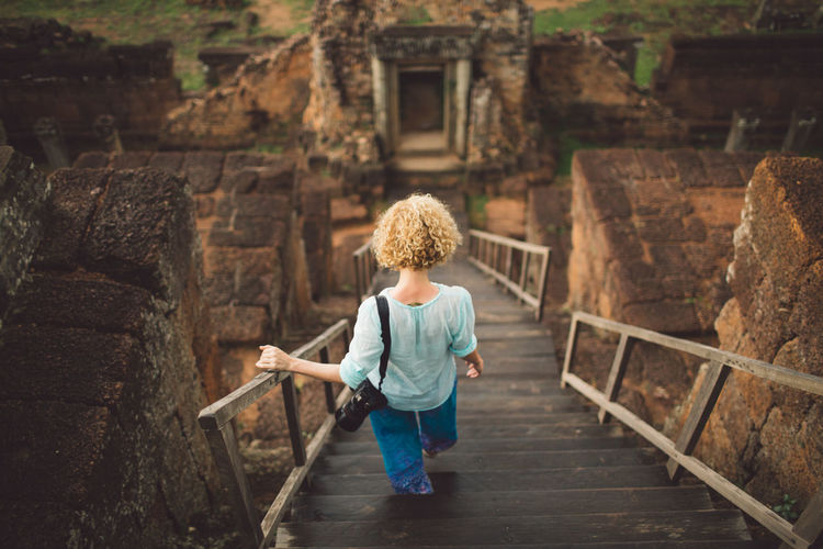 Rear view full length of woman moving down on steps at temple