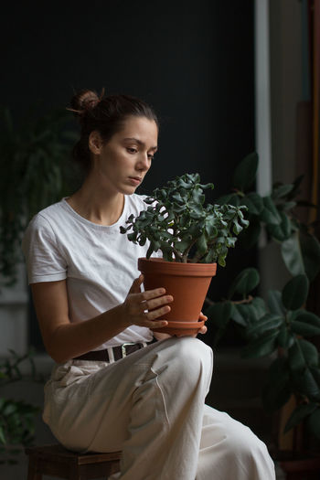 Young woman looking at potted plant