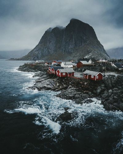 Houses by sea against mountains and sky