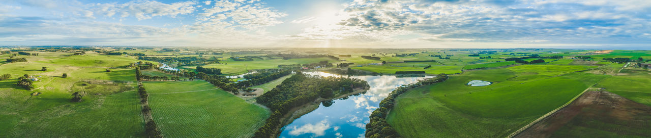 Wide aerial panorama of river flowing through grasslands and pastures in australia at sunset