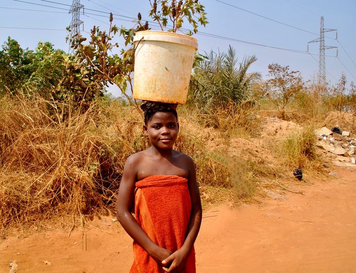 A girl with a water bucket on her head