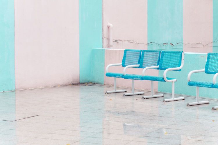 Empty chairs against wall in swimming pool