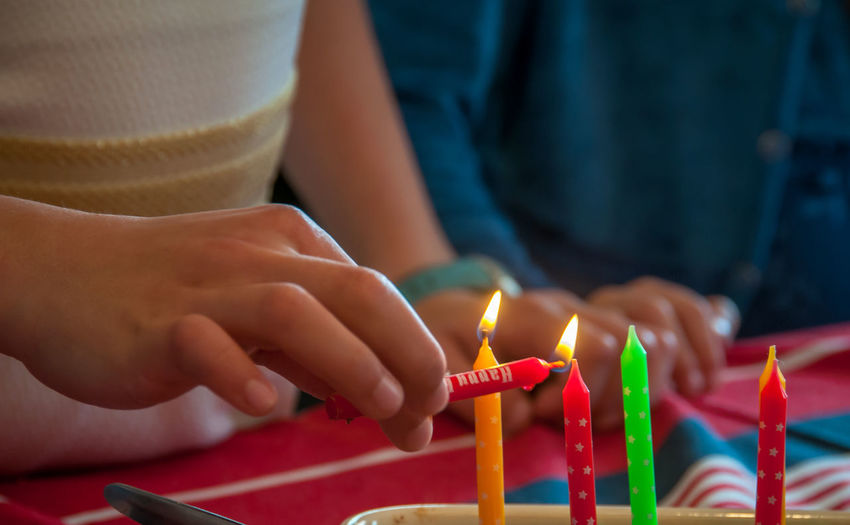 Close-up of girl lighting birthday candles