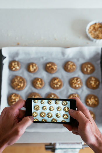 Overhead view of a young man taking a photo of his home-made cookies