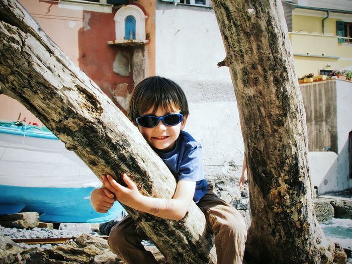 Portrait of happy boy holding tree trunk