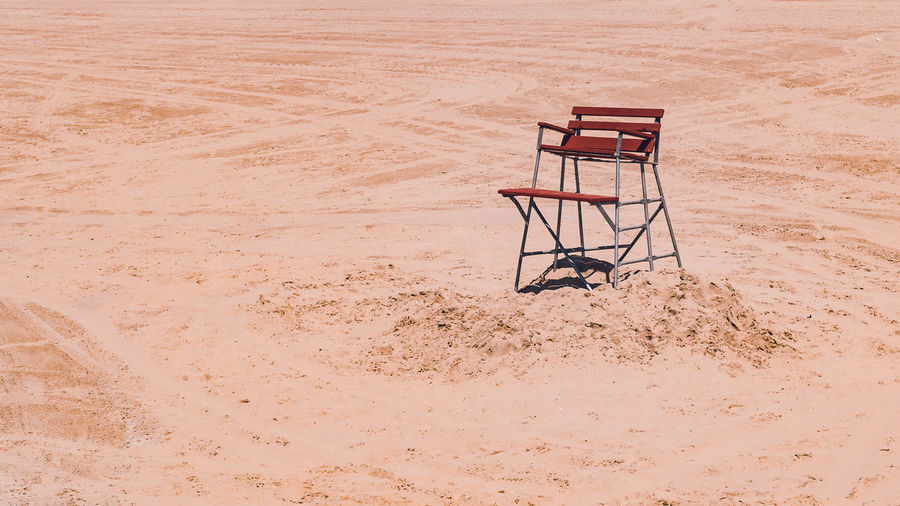 Empty chair on sand at beach