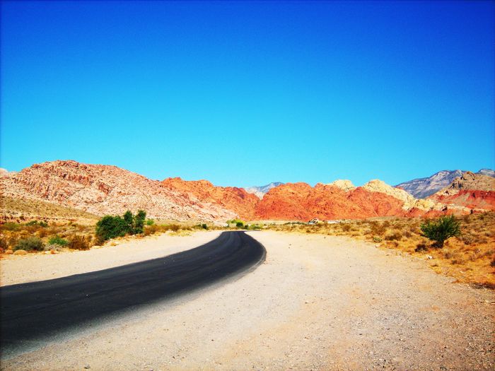 Road in desert against clear blue sky