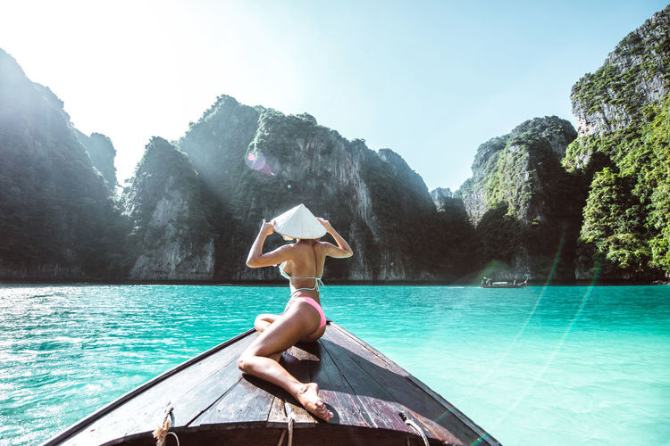 Rear view of woman wearing bikini in boat on sea