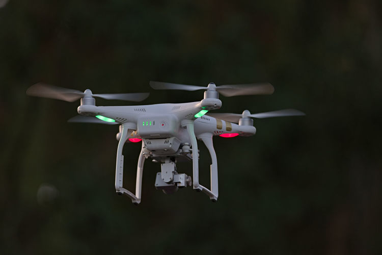 Rear view of professional quadcopter camera drone hovering. looking from behind