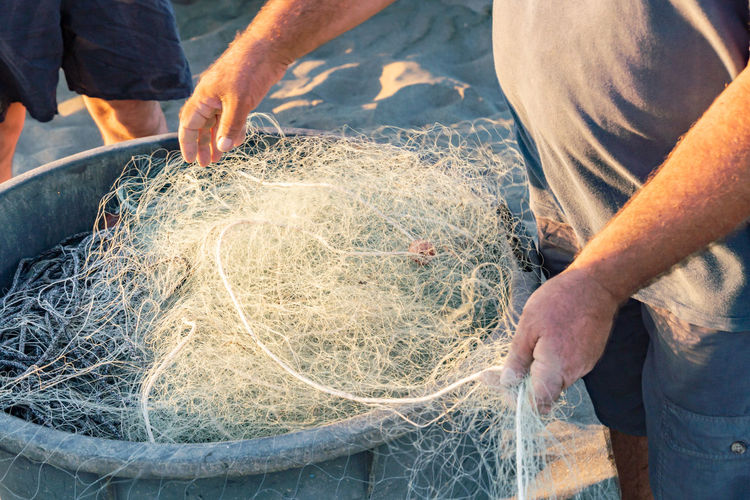 Midsection of man holding fishing net and container