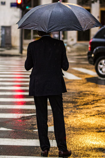 Rear view of man on wet street during monsoon