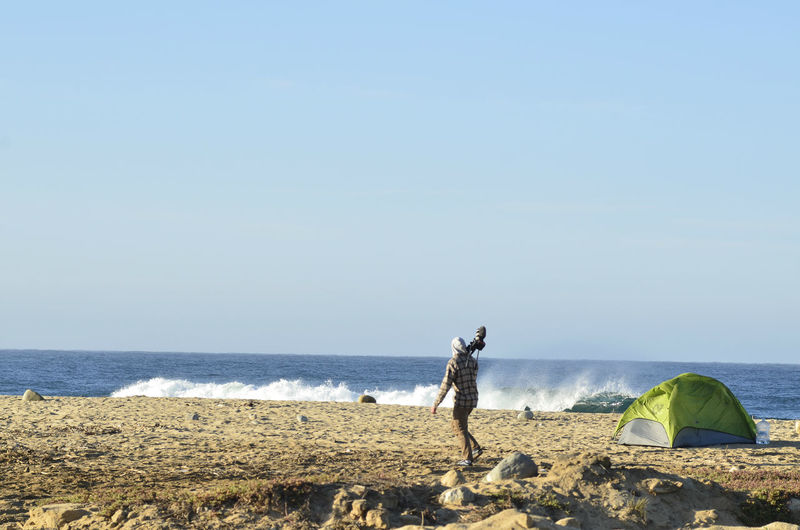 Cameraman walking on ocean beach early morning carrying his video camera baja california sur, mexico