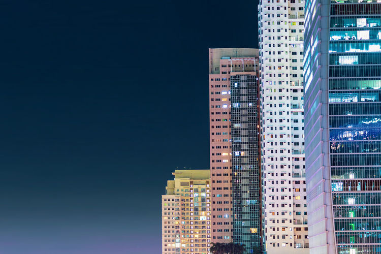 Low angle view of illuminated buildings against clear sky at night