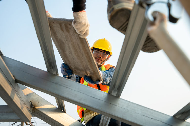 Roofer installing concrete roof tile on top roof on the house un