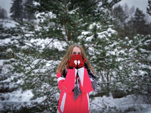 Young woman standing against trees