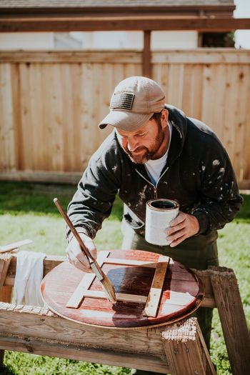 Man painting wood outdoors
