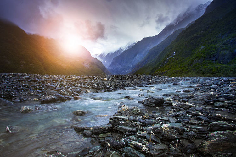 Scenic view of river flowing through rocks against sky