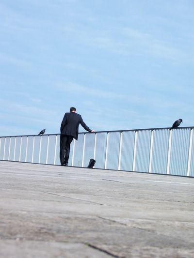 Businessman standing by railing against sky