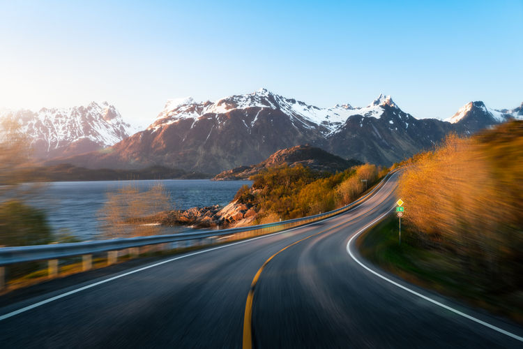 Road by lake against snowcapped mountains