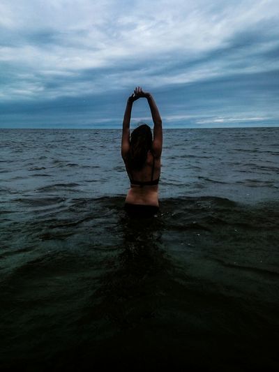 Rear view of woman in sea against sky