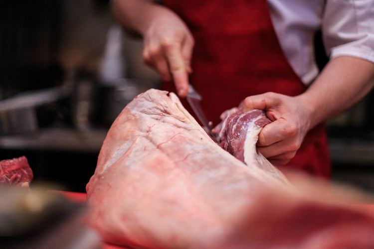 Close-up of butcher cutting meat at table