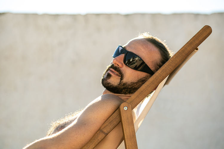 Man with sunglasses on a sun lounger at sunset