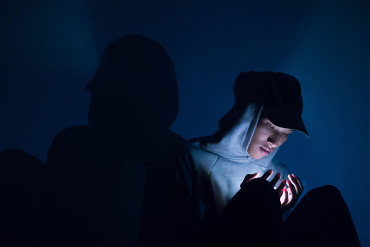 Young man using mobile phone in dark