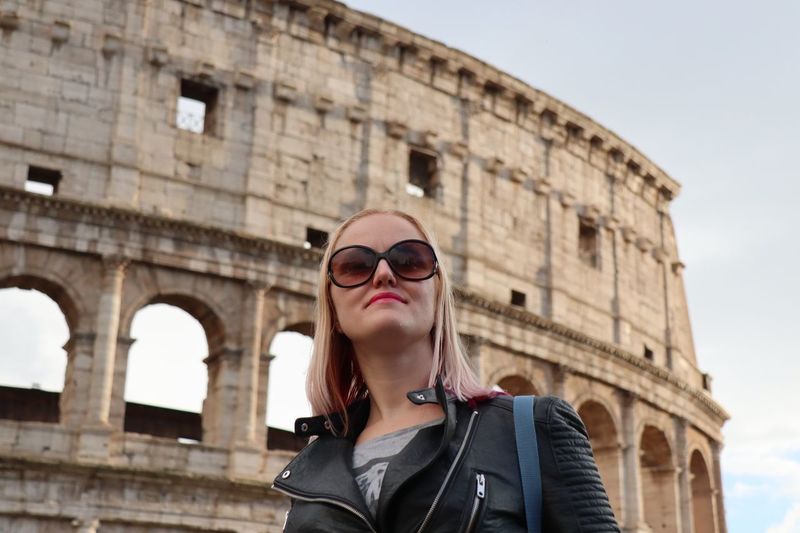 Mid adult woman wearing sunglasses against coliseum