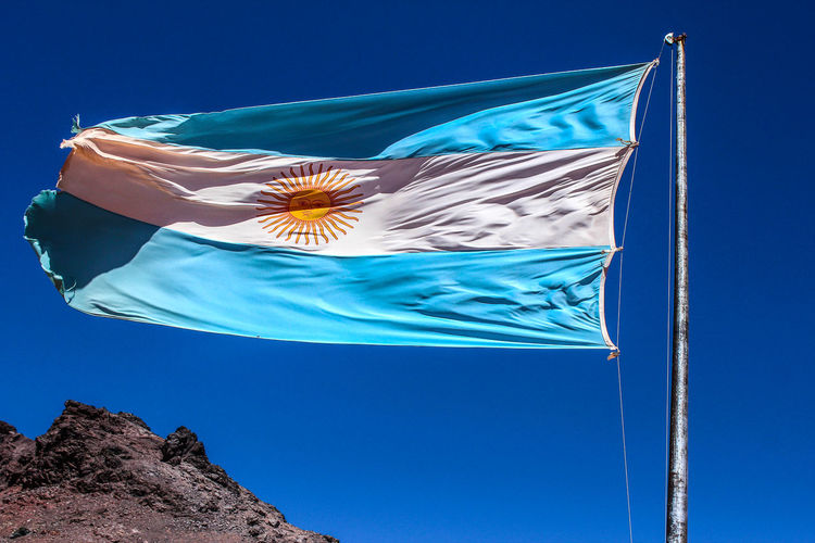 Low angle view of argentinian flag against clear blue sky
