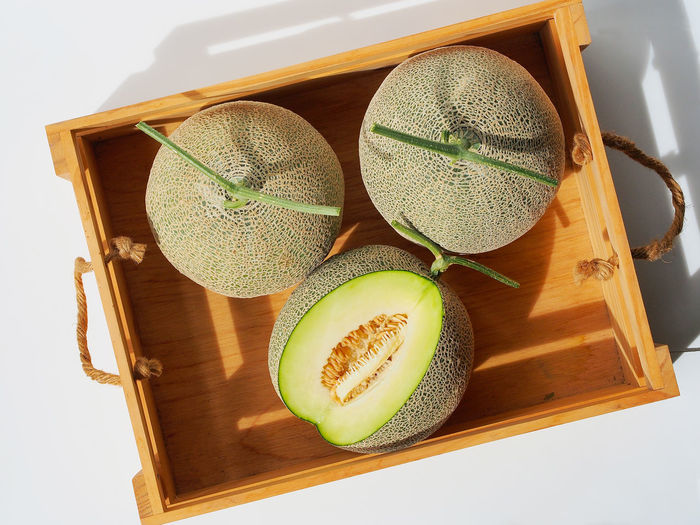 High angle view of melon on fruit crate with sunlight