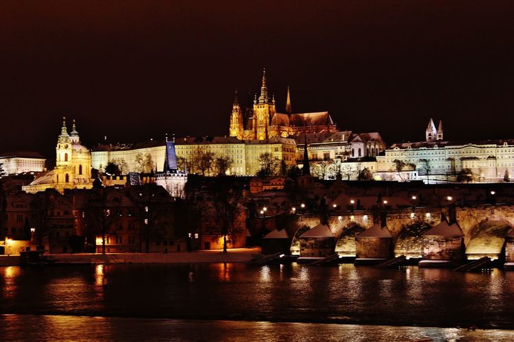 Illuminated prague castle by vltava river at night