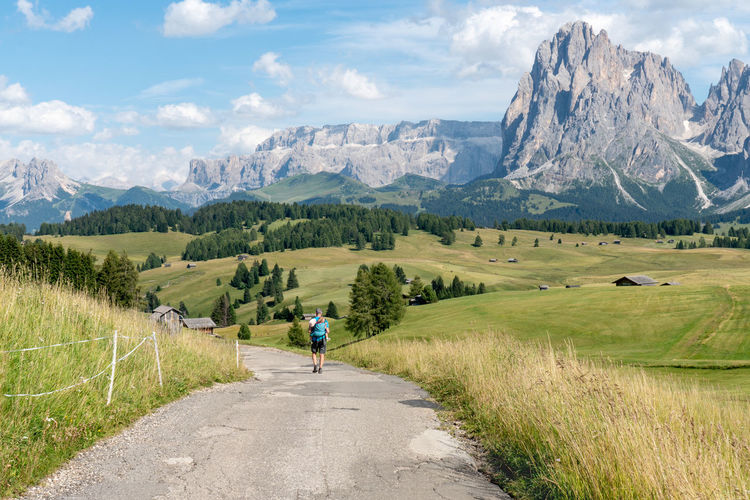 Rear view of man walking on road amidst sasso lungo italian mountains 