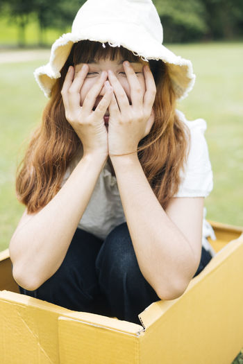 Smiling young woman sitting in cardboard box outdoors