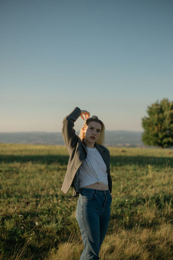 Portrait of a young woman standing in a field during sunset