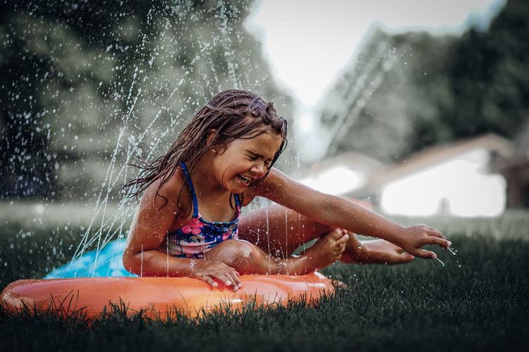 Girl enjoying sprinklers in yard