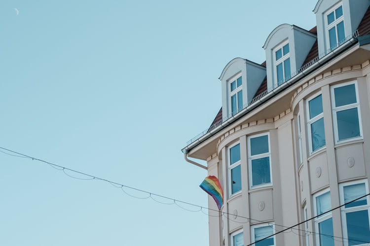 Low angle view of building with rainbow flag against sky