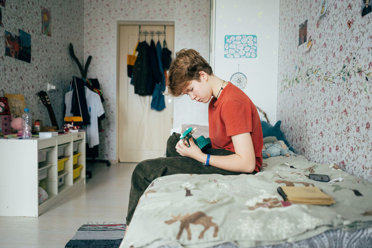 Side view of young man using mobile phone at home