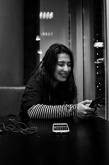 Smiling young woman using smart phone at home
