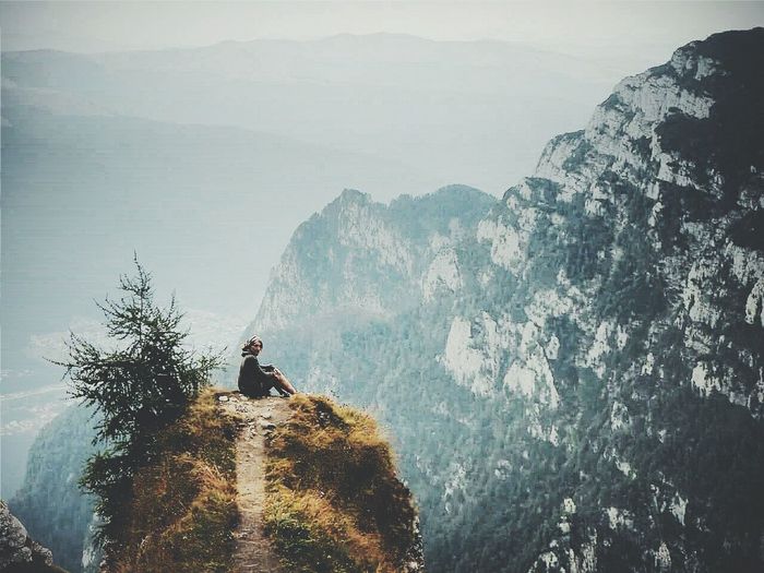 Woman sitting on mountain peak 